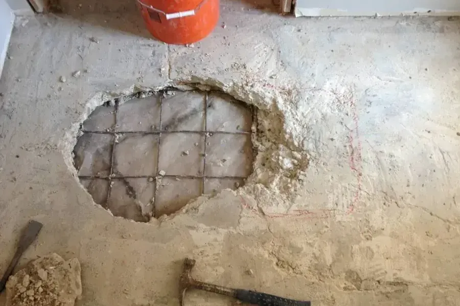 Concrete slab broken open to reach a leaking pipe under a house